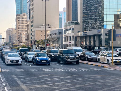 Ulica w kuwait city z dużym ruchem i nowoczesnymi wieżowcami po obu stronach
