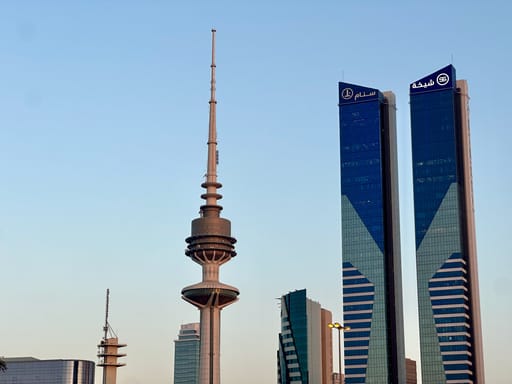 Widok zabudowy w kuwait city z wieżą telekomunikacyjną i nowoczesnymi wieżowcami.