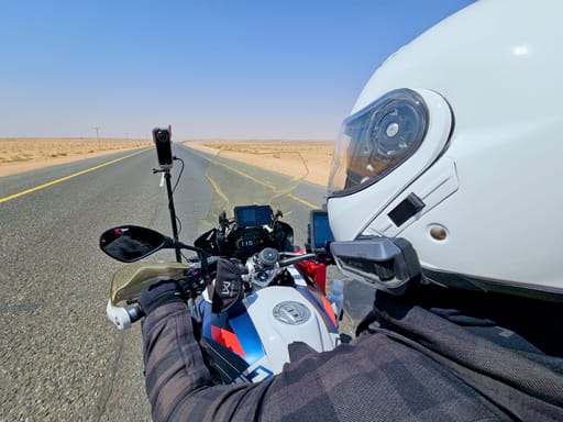 Motocyklista na pustynnej drodze w arabii saudyjskiej z kamerą na motocyklu.