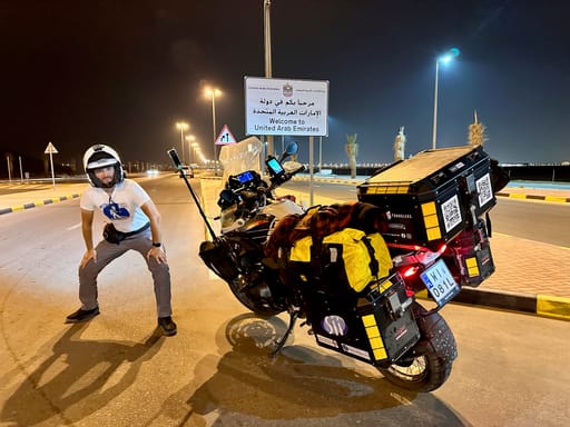 Motocyklista przy granicy lądowej al ktab z omanem w uae, obok znaku welcome to united arab emirates
