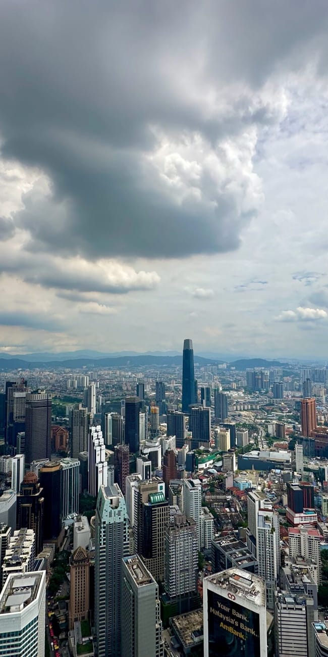 Panorama kuala lumpur z wieżowcami pod dramatycznym, zachmurzonym niebem.