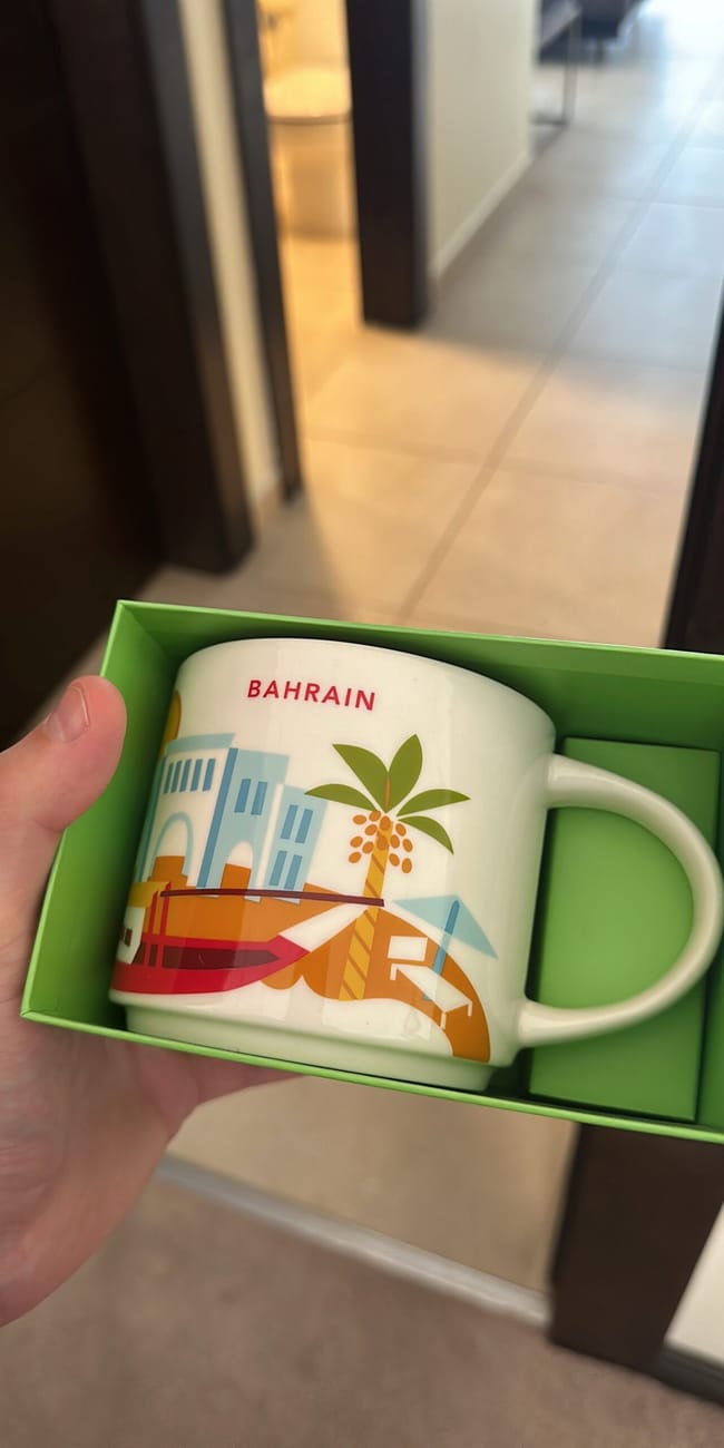 Kubek z napisem bahrain i kolorową ilustracją palm w zielonym pudełku