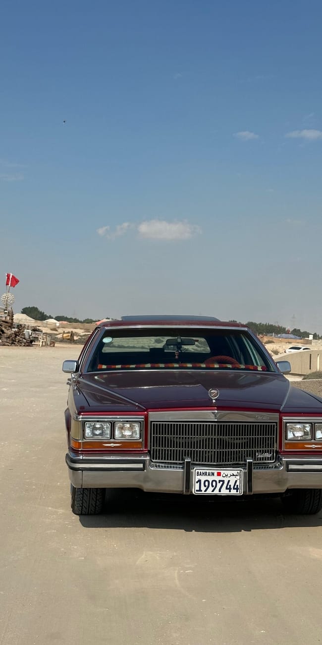Klasyczny bordowy cadillac na drodze w bahrajnie, pod bezchmurnym niebem.
