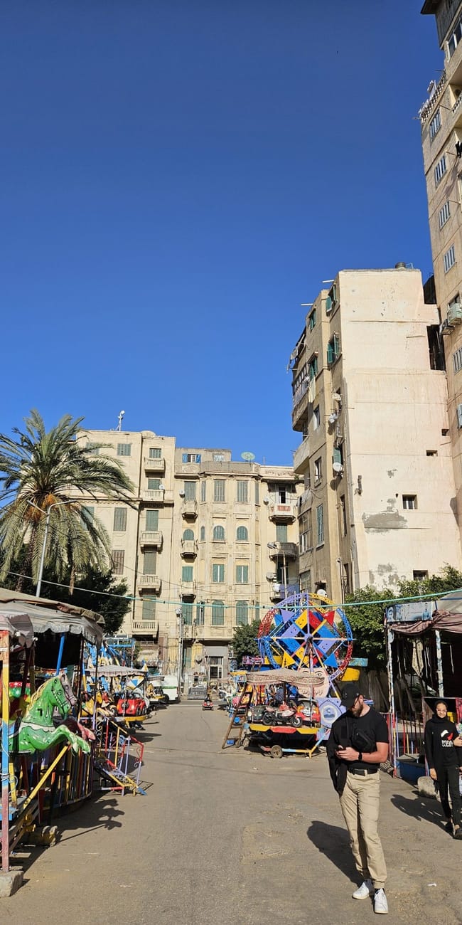 Sidi morsi abu al-abbas mosque w aleksandrii, otoczony straganami i wysokimi budynkami.