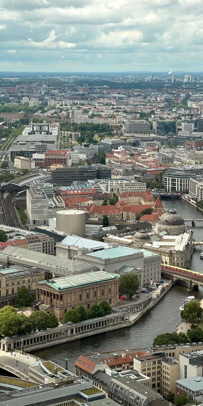 Panorama berlina z rzeką szprewą, mostami i zabudową miejską pod pochmurnym niebem.