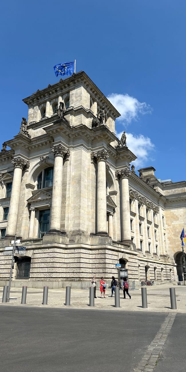 Berlin, gmach reichstagu pod błękitnym niebem z flagami przed wejściem