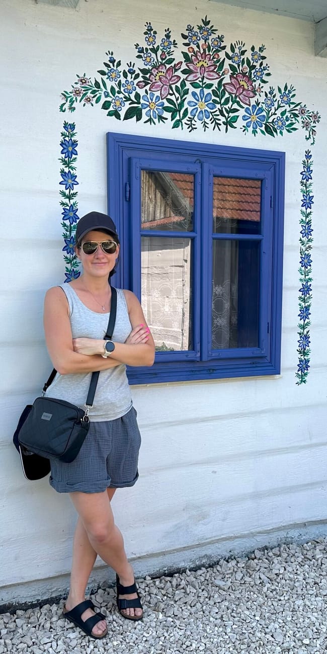 Homestead felicji curylowej w zalipiu z malowanymi kwiatami na białej ścianie i niebieskim oknem