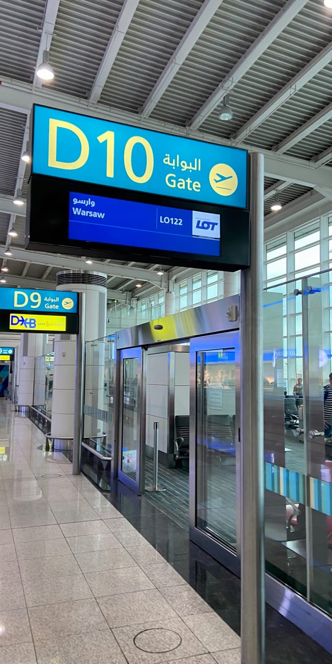 Bramka d10 na lotnisku w dubaju z informacją o locie do warszawy.