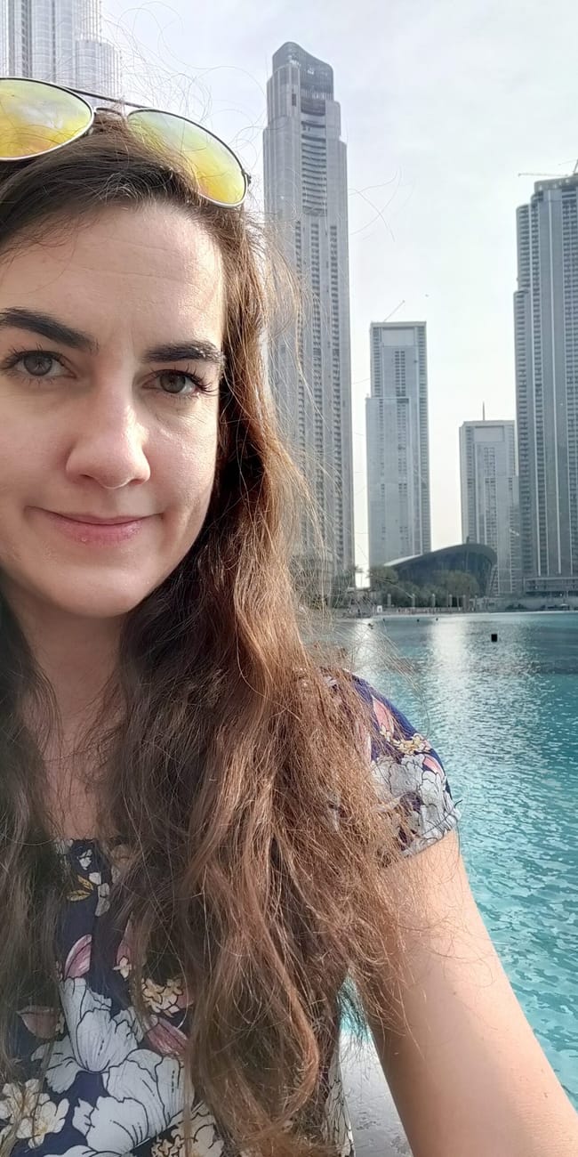 Selfie przy dubai fountain w dubaju, z wieżowcami i turkusową wodą w tle