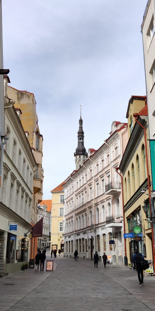 Tallinn, estonia old town street with white buildings and st. Olaf’s church spire in the distance