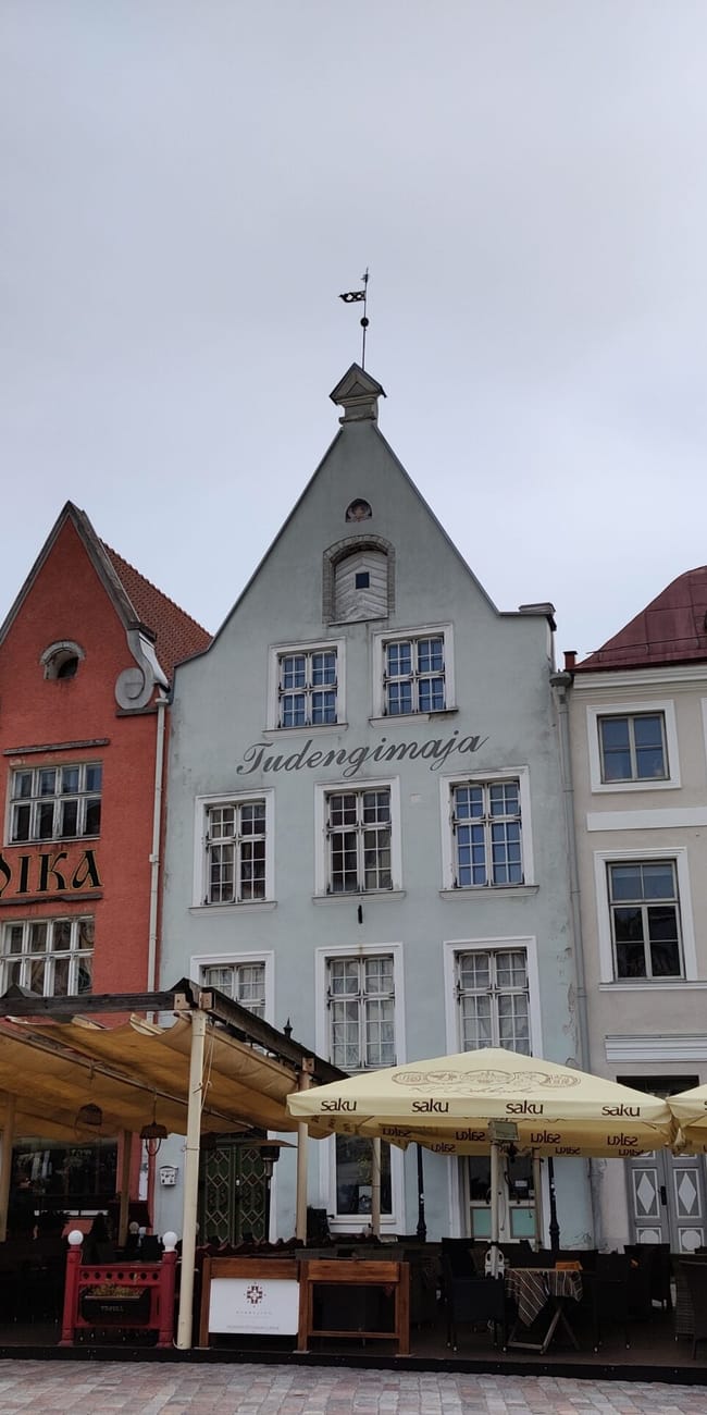 Tallinn article photo of colorful historic buildings with sign “troika” and café umbrellas in estonia
