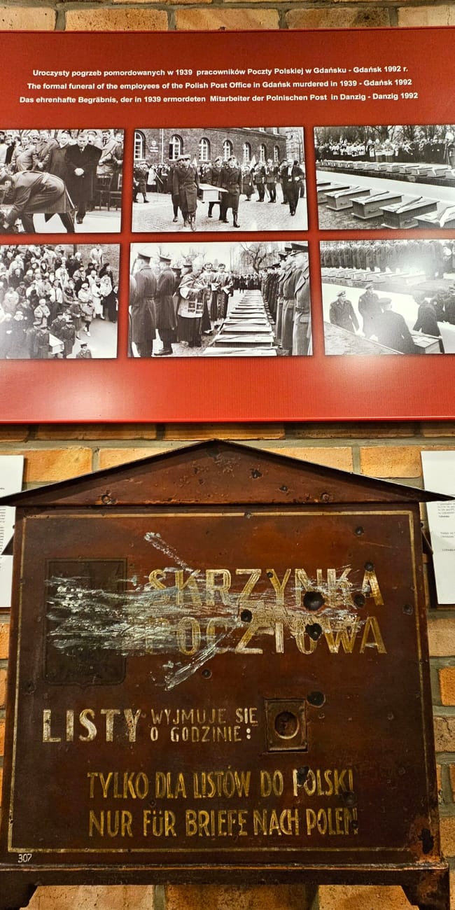 Ekspozycja w muzeum poczty polskiej w gdańsku z historyczną skrzynką pocztową i panelem zdjęć.