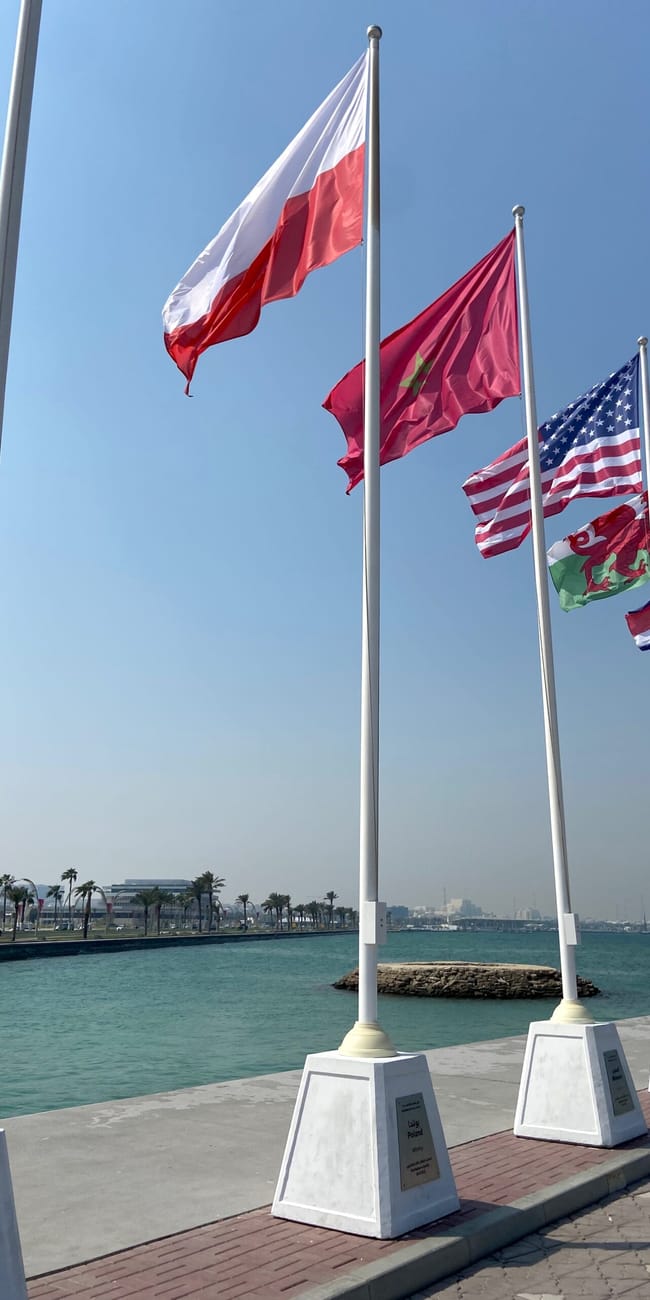 Rząd flag przy nadbrzeżu w doha w katarze, powiewające na wietrze pod błękitnym niebem