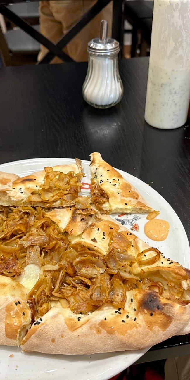 Lahmacun z cebulą na talerzu w restauracji w zurychu, obok napoju i sosów