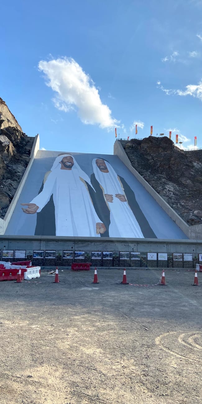 Mural w hatta w zea przedstawiający dwóch mężczyzn na stromej betonowej ścianie w górach.