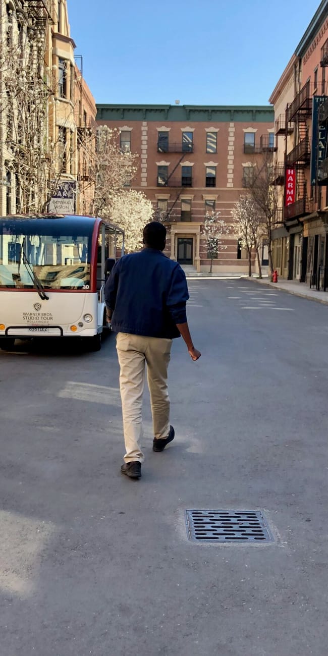 Ulica na planie warner bros. W los angeles z jadącym mini autobusem i mężczyzną na środku jezdni
