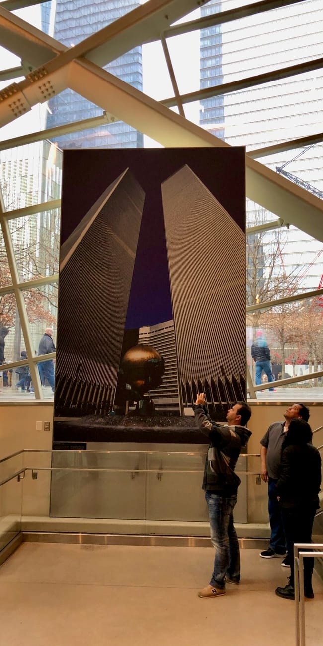 Wnętrze 9/11 museum w nowym jorku z dużą fotografią bliźniaczych wież i zwiedzającymi.