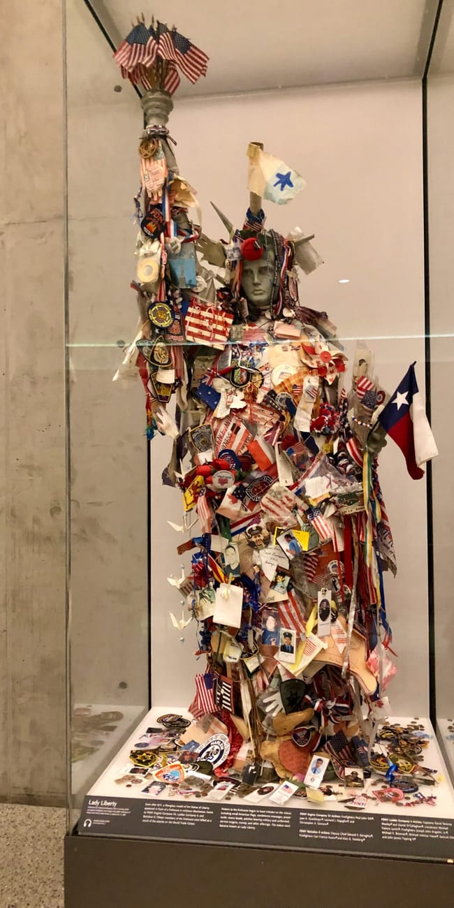 Figura statui wolności w 9/11 museum w nowym jorku, ozdobiona flagami i pamiątkami.