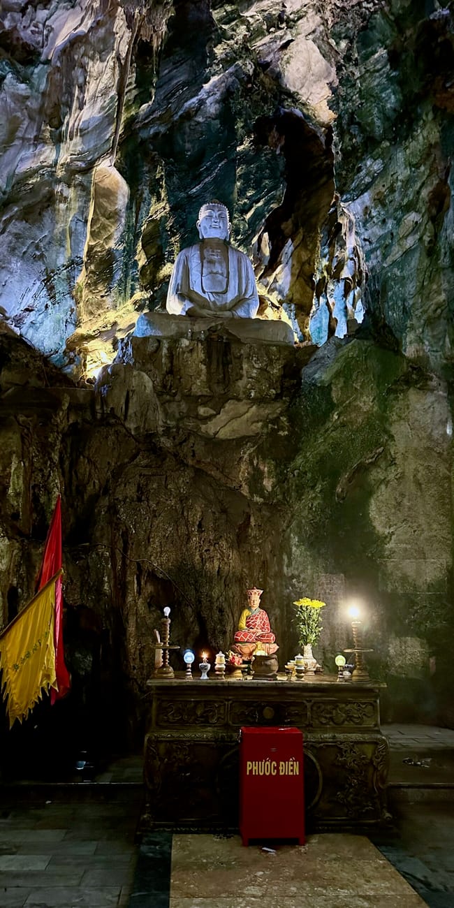 Świątynne wnętrze jaskini na da nang marble mountains z posągiem buddy i ołtarzem.