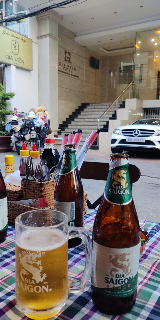 Ogródek przed hotelem gia viên w ho chi minh foods z butelkami i kuflem piwa bia saigon na stole
