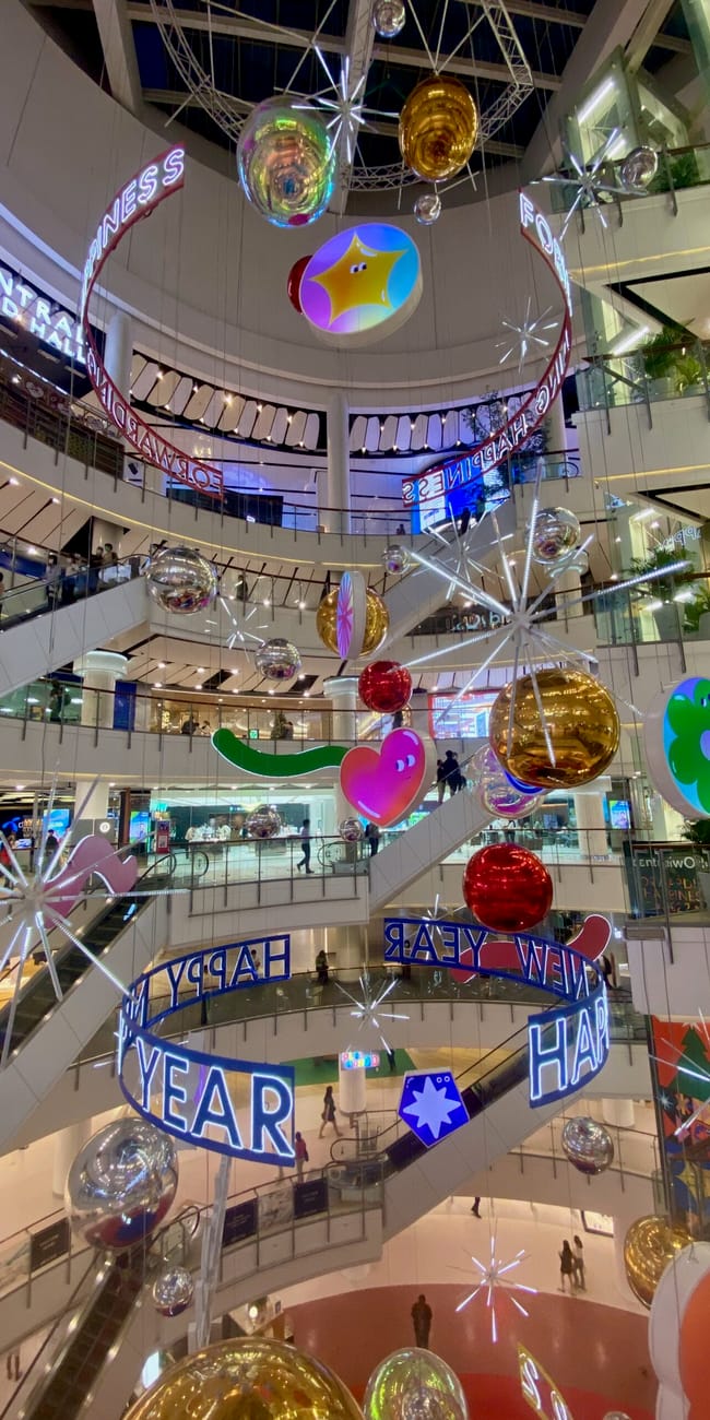 Wnętrze centrum handlowego centralworld w bangkoku z noworoczną dekoracją świetlną i kulami wiszącymi.