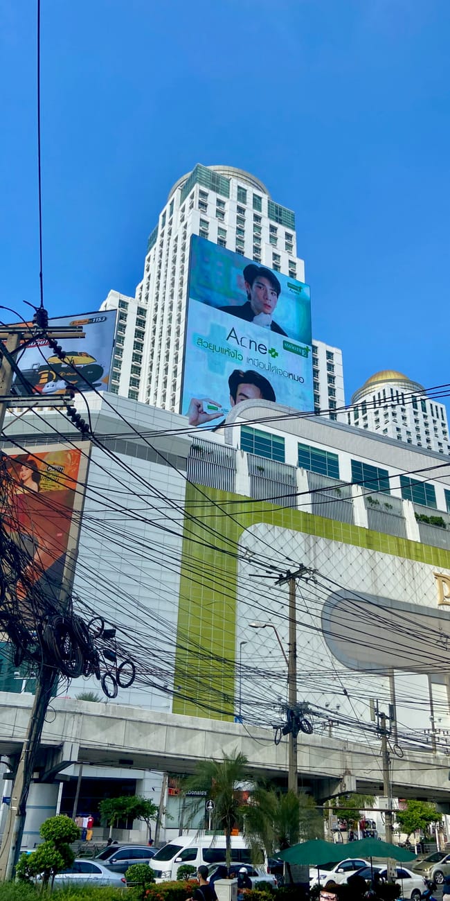 Bangkok z wysokimi wieżowcami, billboardami i plątaniną przewodów na pierwszym planie