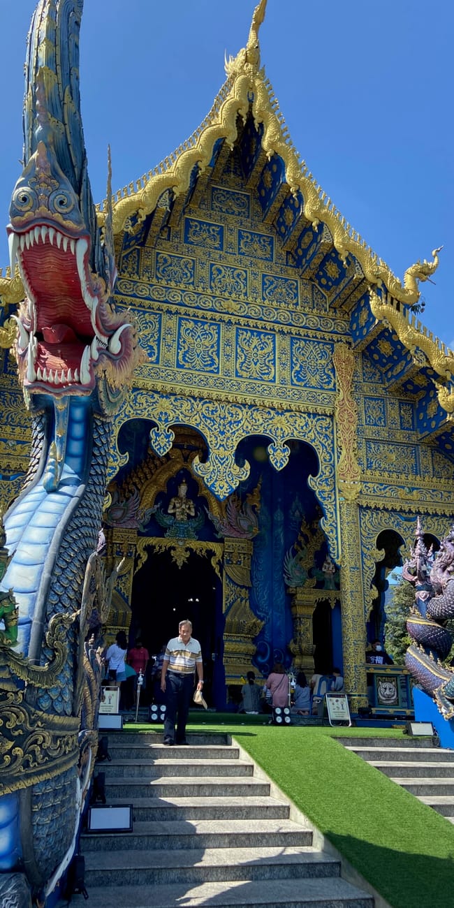 Wat rong suea ten w chiang rai z bogato zdobionym, niebiesko-złotym wejściem i rzeźbą węża.