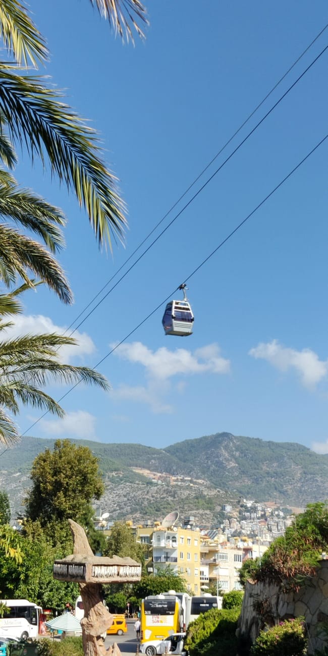 Kolejka linowa nad palmami z widokiem na wzgórza przy alanya castle, turcja
