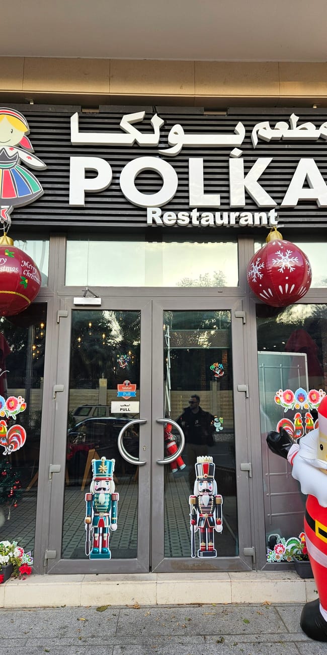 Wejście do polka restaurant w doha, udekorowane świątecznie z dużą figurą świętego mikołaja.