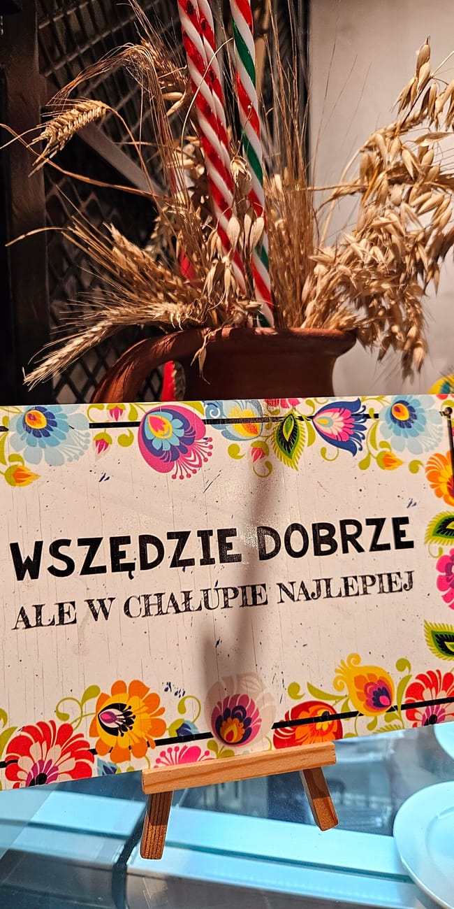 Tabliczka z napisem „wszędzie dobrze, ale w chałupie najlepiej” w restauracji polka w dosze.