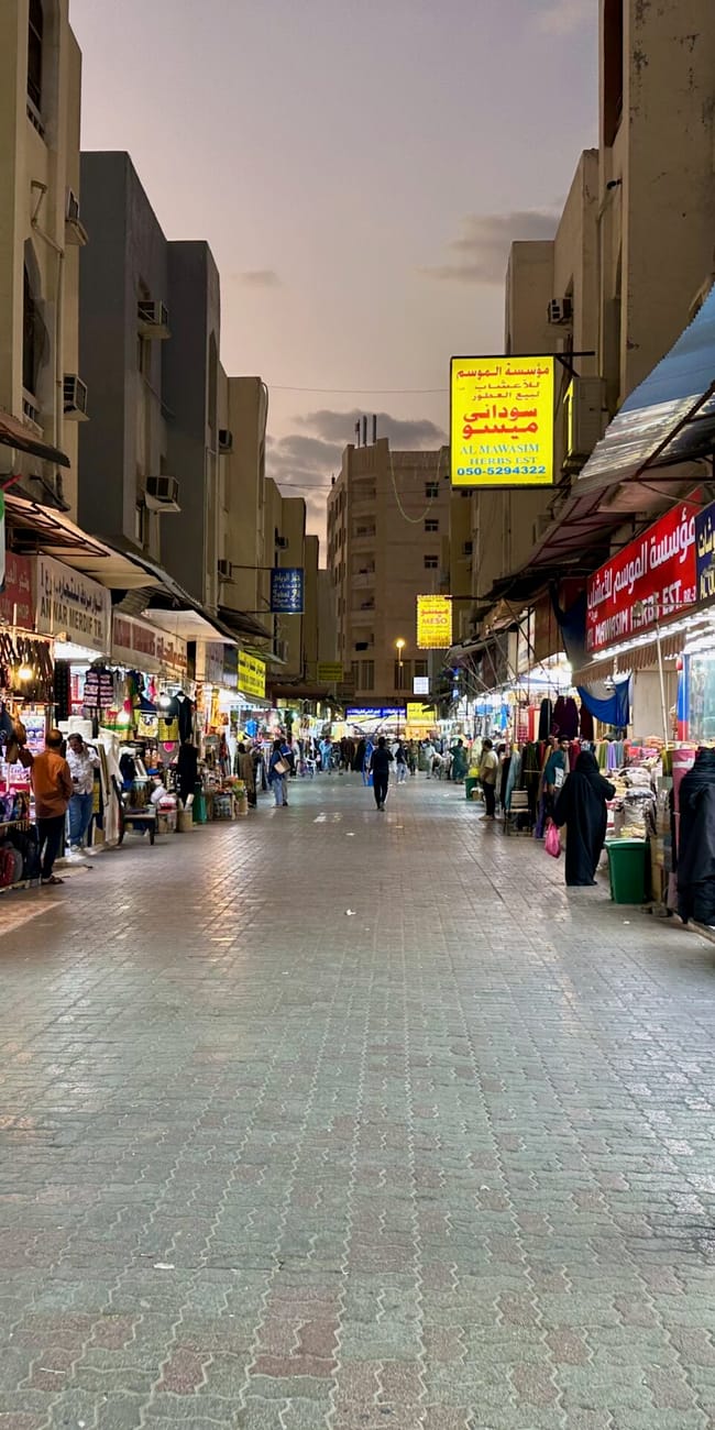 Targ al ghuwair market w sharjah z alejką sklepów i przechodniami.