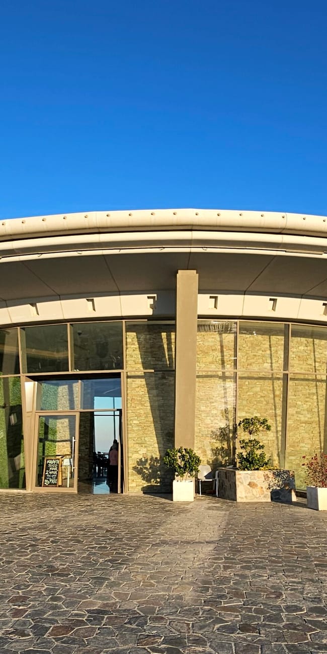 Sharjah al suhub rest area w zea, okrągły pawilon z przeszkloną fasadą na tle błękitnego nieba.