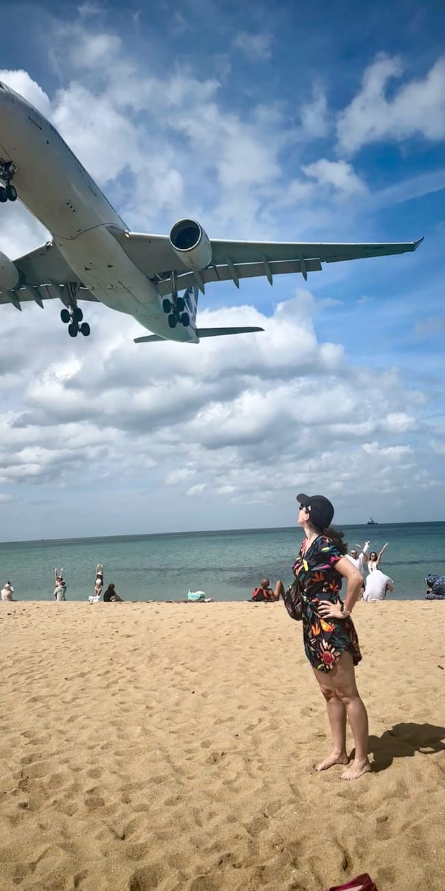 Samolot nisko przelatuje nad plażą w phuket, a turyści obserwują lądowanie.