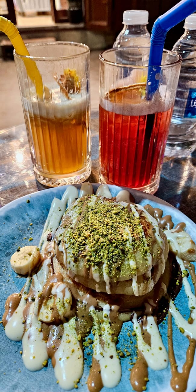Baghdad foods w bagdadzie: deser z pistacjami i dwa kolorowe napoje z rurkami.
