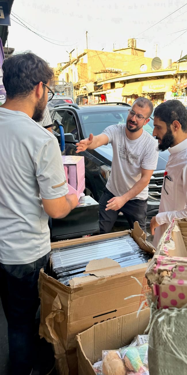Ulica w erbil: kilku mężczyzn przegląda towary przy stoisku z kartonami.