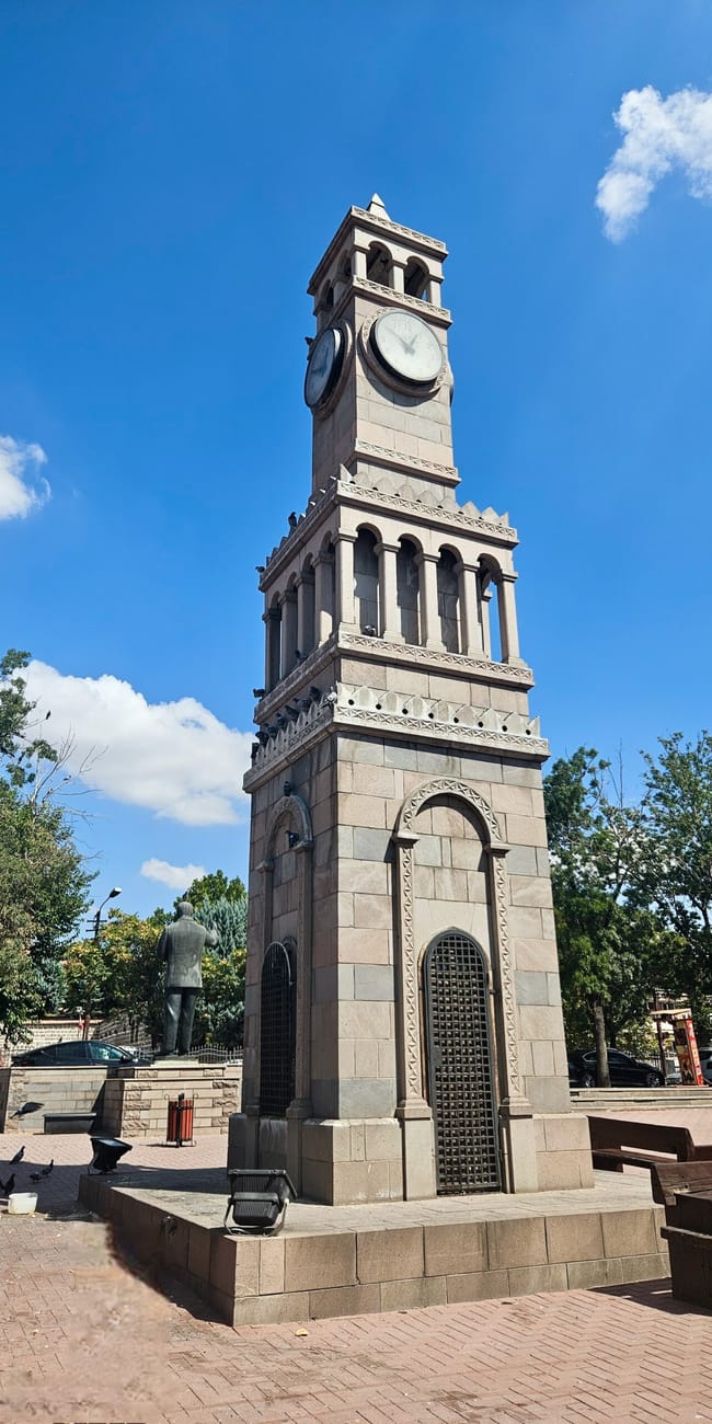 Clock tower and ornate stone building at ankara historical houses, turkey, under a blue sky with clouds