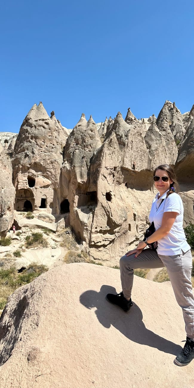 Turcja, goreme zelve museum: kobieta stoi na skale na tle tufowych formacji i wykutych jaskiń.