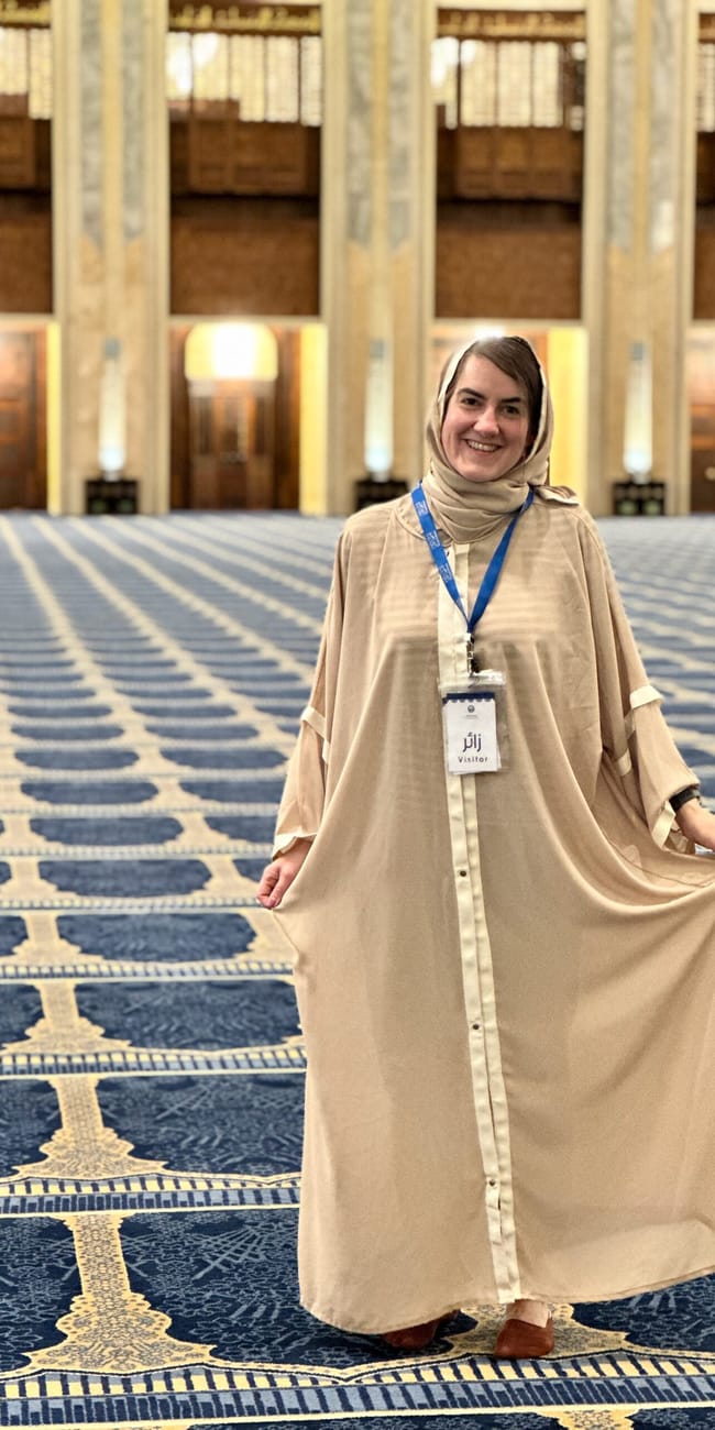 Visitor at kuwait city grand mosque standing on a blue patterned prayer carpet