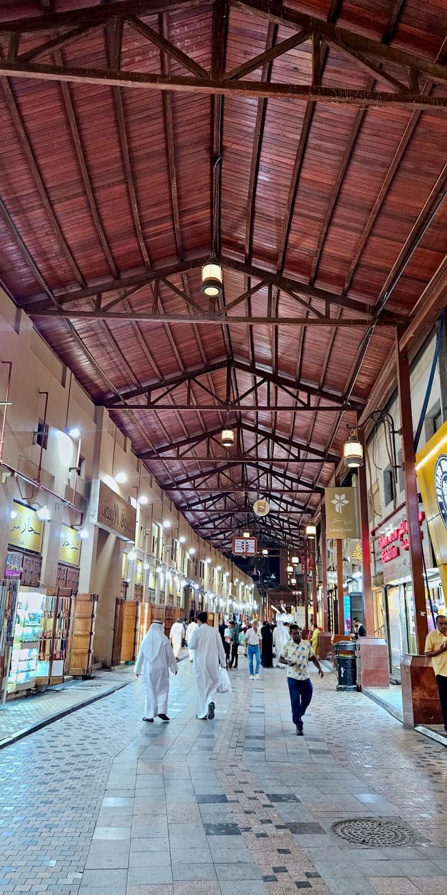 People walking through an covered market corridor in kuwait’s al mubarakiya city