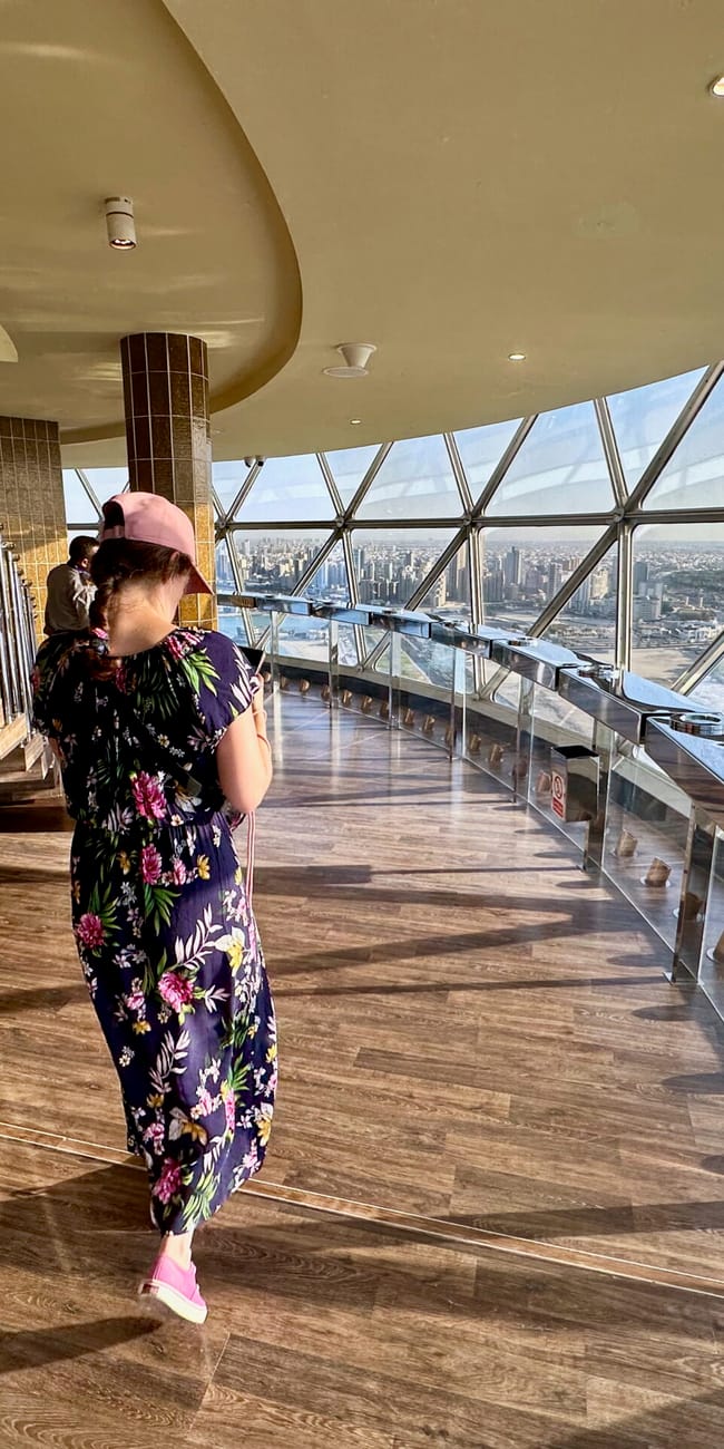 Person in a floral dress walking on the observation deck at kuwait city towers with city skyline views
