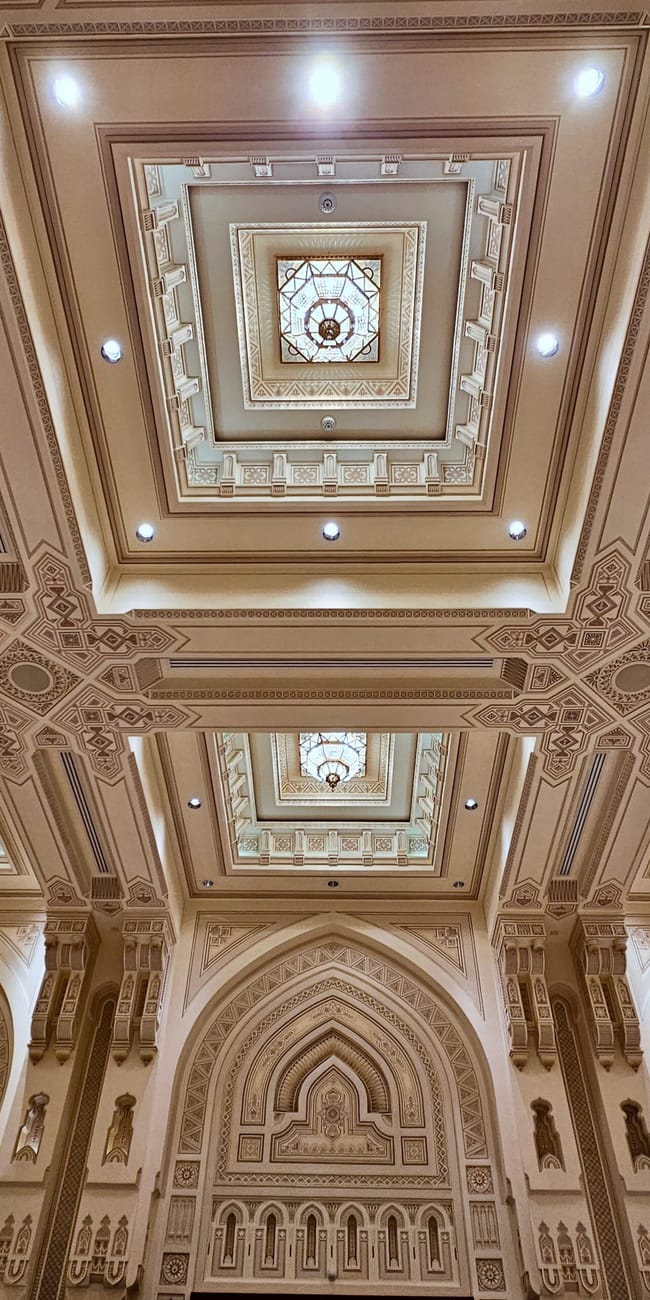 Bogato zdobiony sufit royal opera house w muskacie w omanie, z geometrycznymi wzorami i świetlikami.