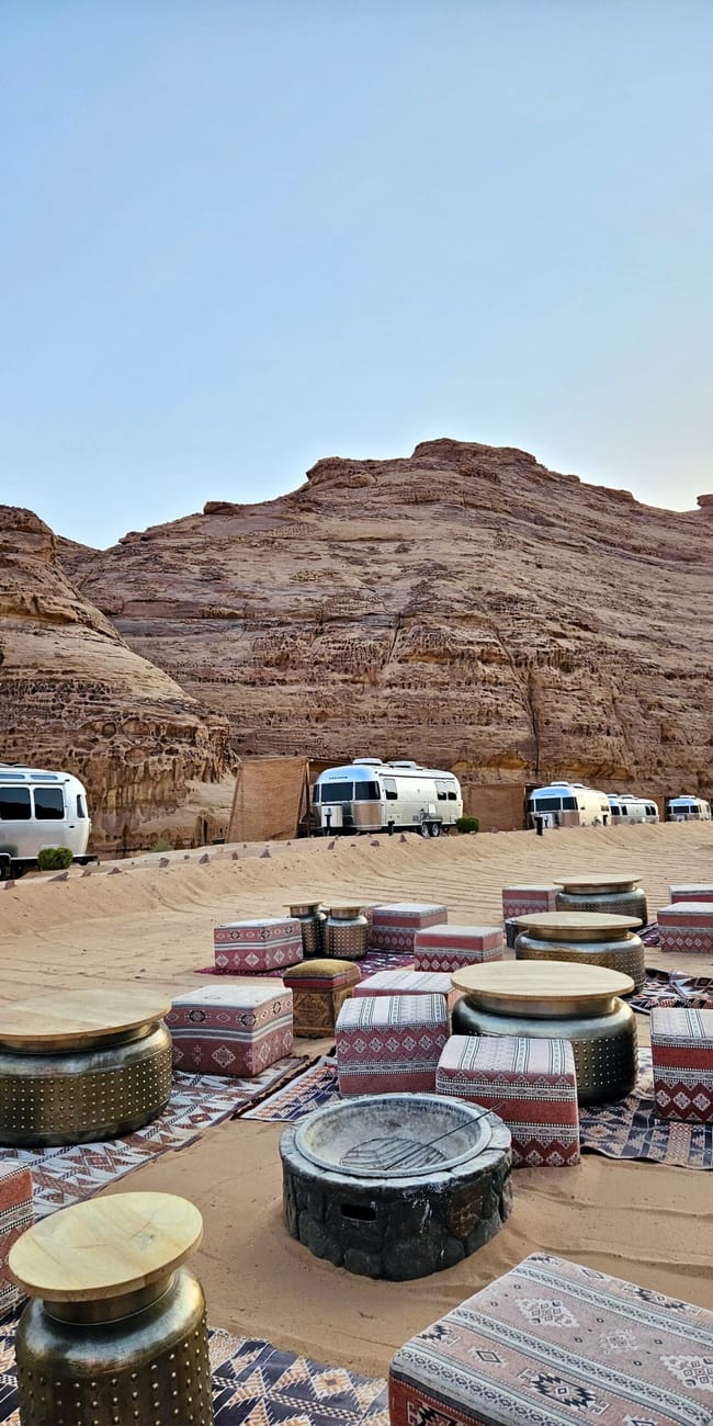 Al ula caravans by habitas in saudi arabia, with patterned seating and vans in a desert valley.