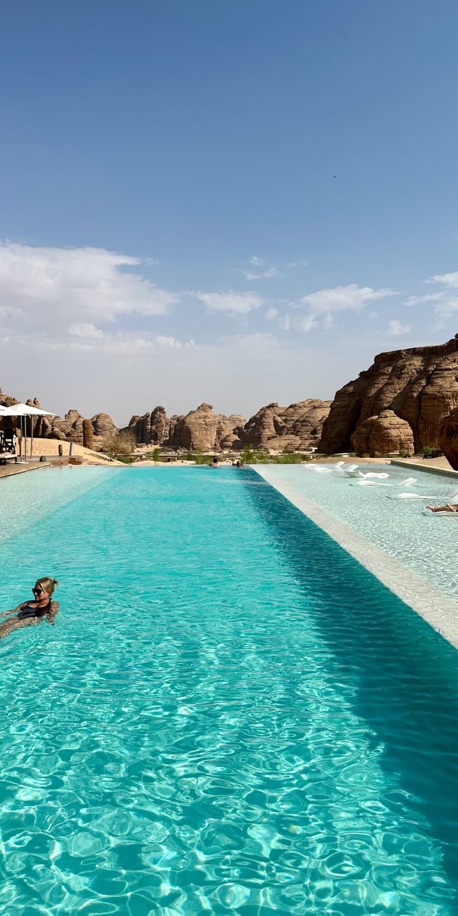 Al ula caravans by habitas pool with turquoise water and desert rock formations in saudi arabia
