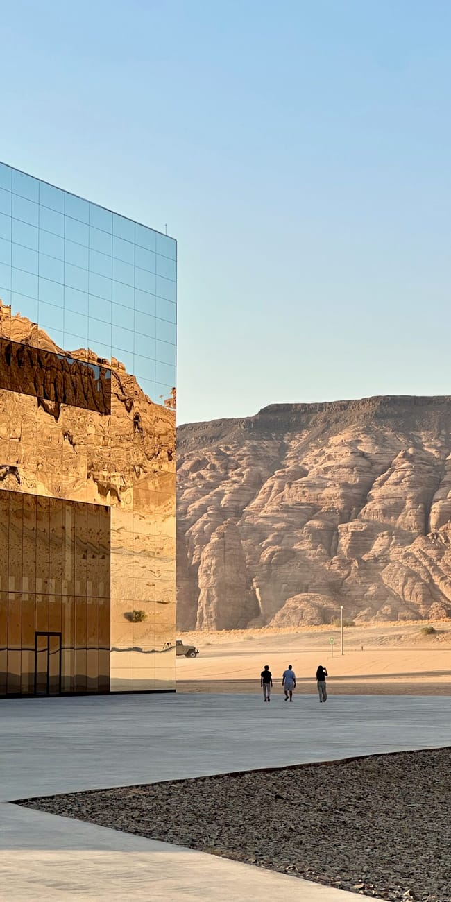 Visitors walk beside the maraya building at al ula maraya, saudi arabia, with desert cliffs in the background