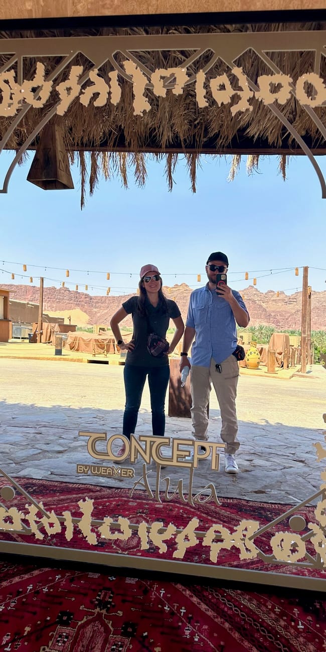 Saudi arabia, al ula old town sign with two people posing under a decorative frame