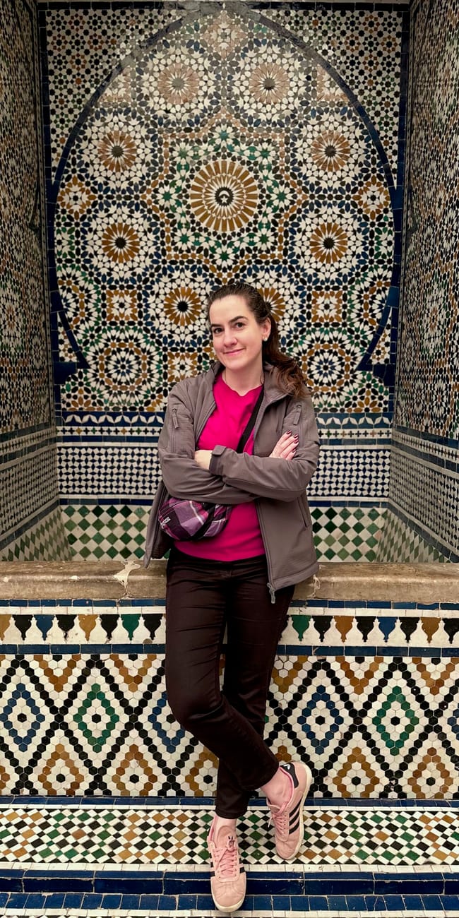 Woman posing in front of the moroccan museum mosaic arch in marrakesh, morocco