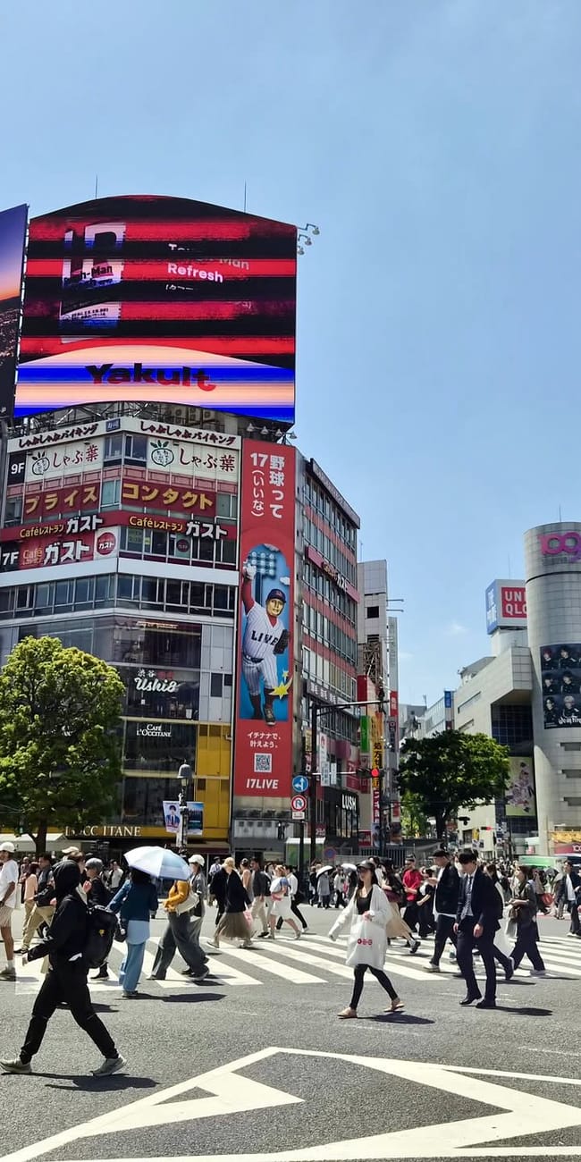 Przejście shibuya w tokio z tłumem pieszych i neonowymi ekranami reklamowymi