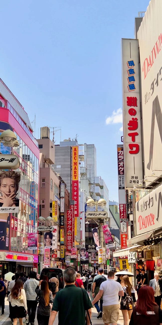 Ulica handlowa w shibuya w tokio, z tłumem przechodniów i wieloma szyldami sklepów i karaoke