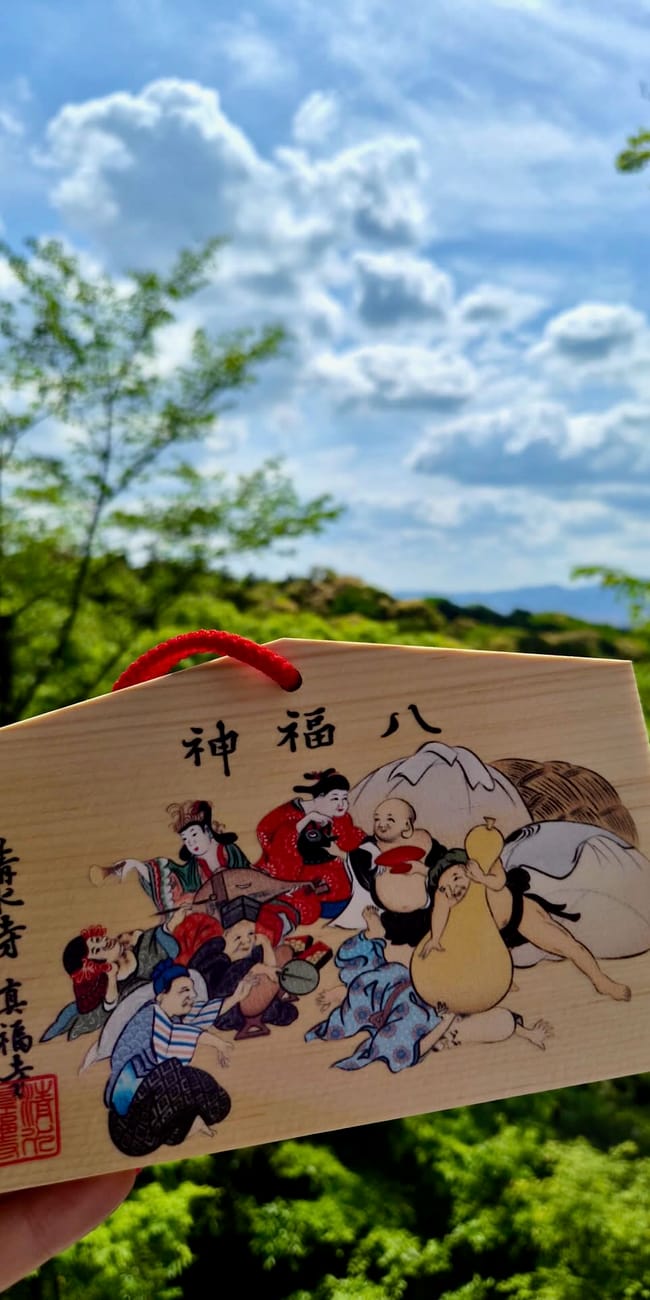 Drewniana tabliczka ema z kiyomizu-dera w kioto na tle zieleni i nieba