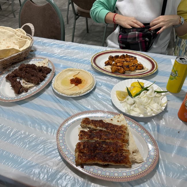 Stół z arabskim jedzeniem w bahrainie: pieczywo, mięso, hummus, cebula i napoje.